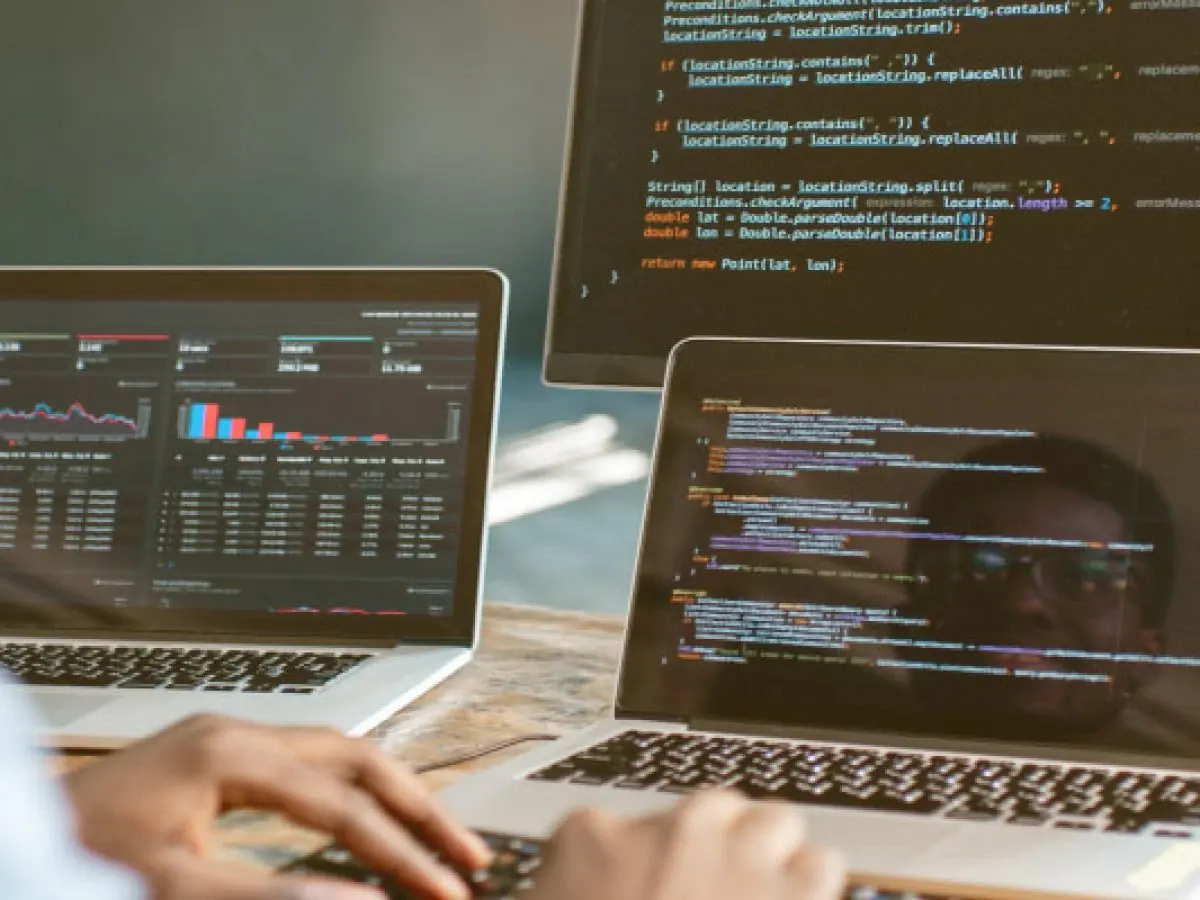 Two laptops showing code and a data dashboard