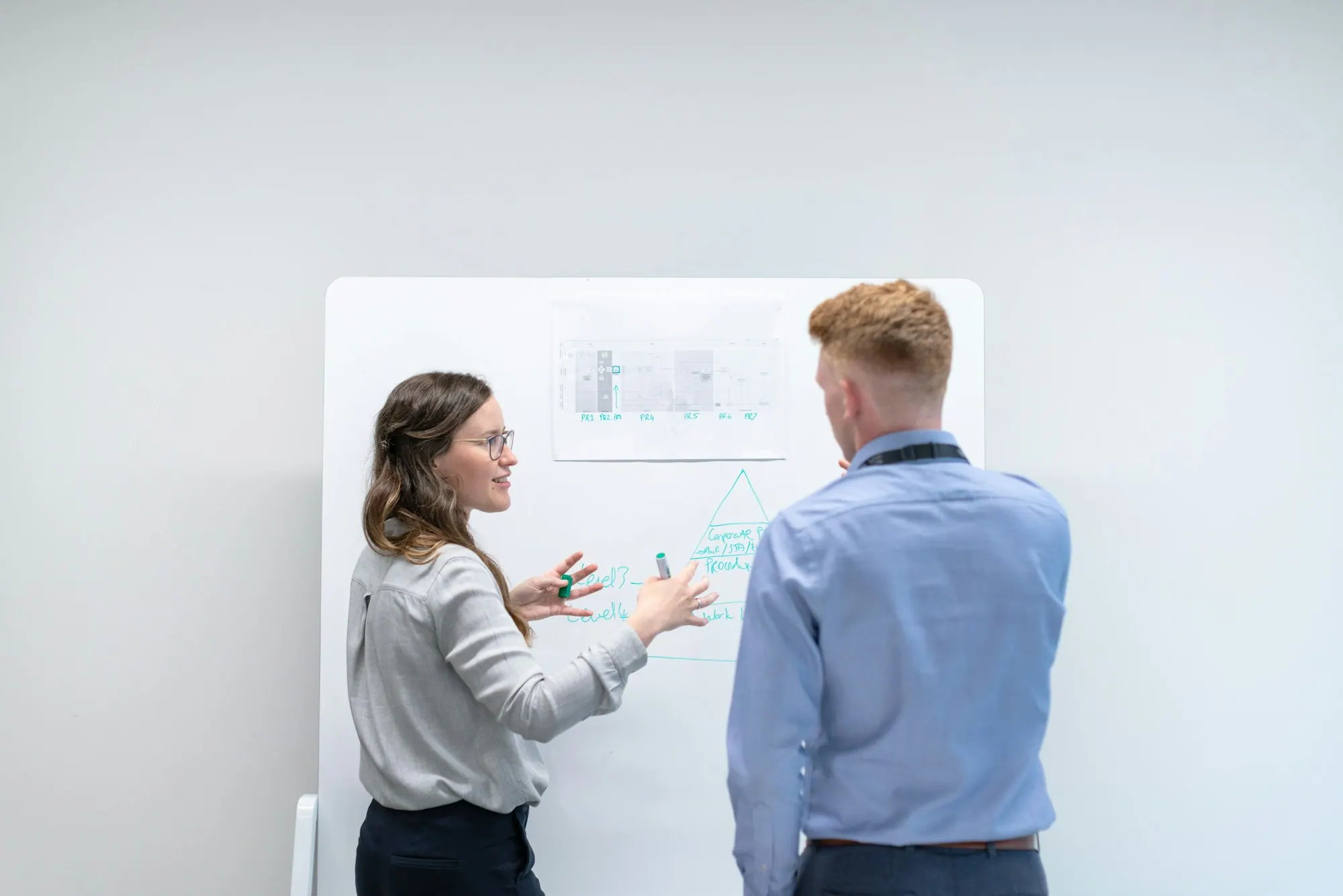 Deux collègues échangent devant un tableau blanc