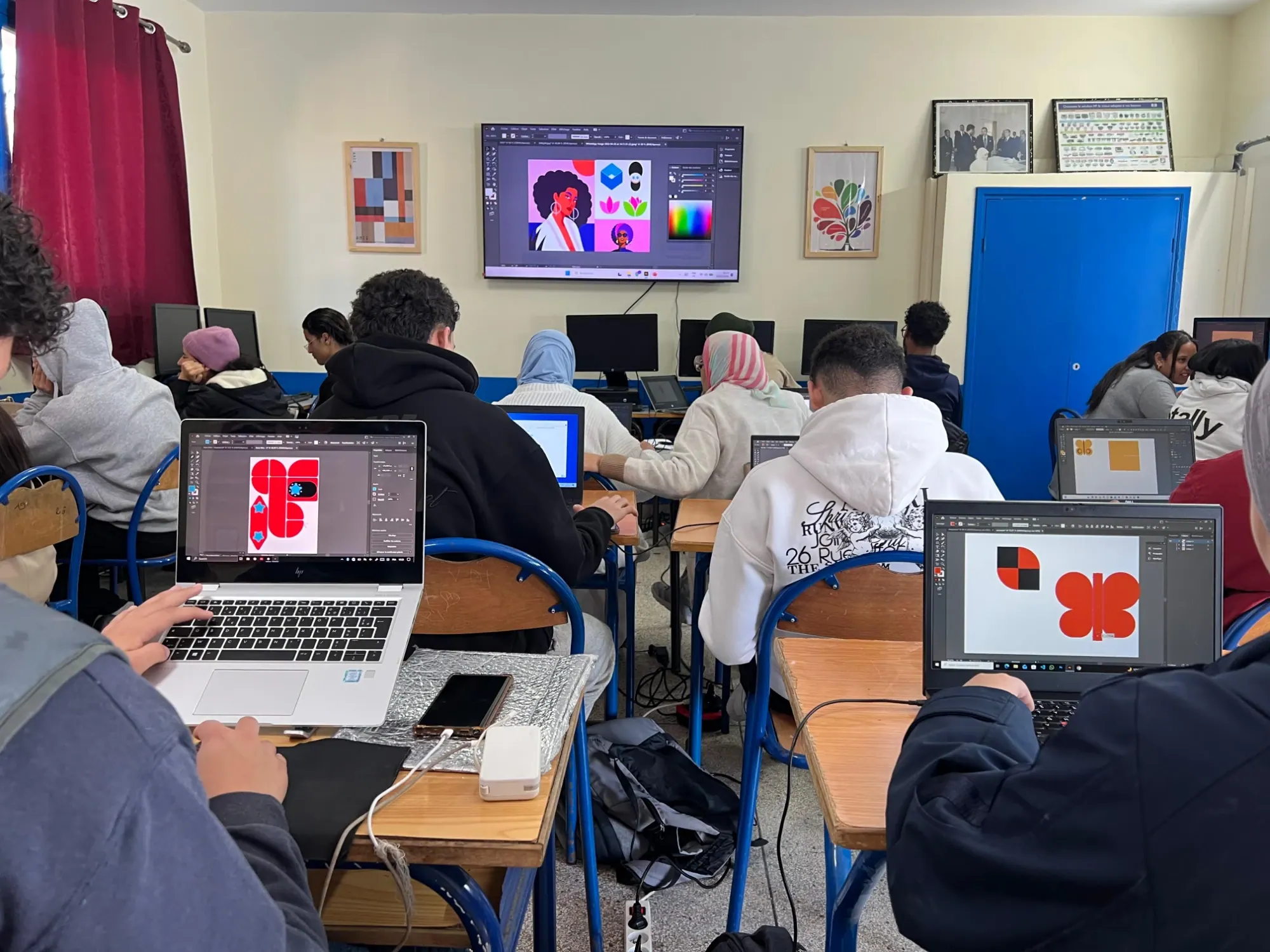 Séance de design graphique : des apprenants reproduisent sur leurs ordinateurs portables les formes vectorielles projetées à l'écran