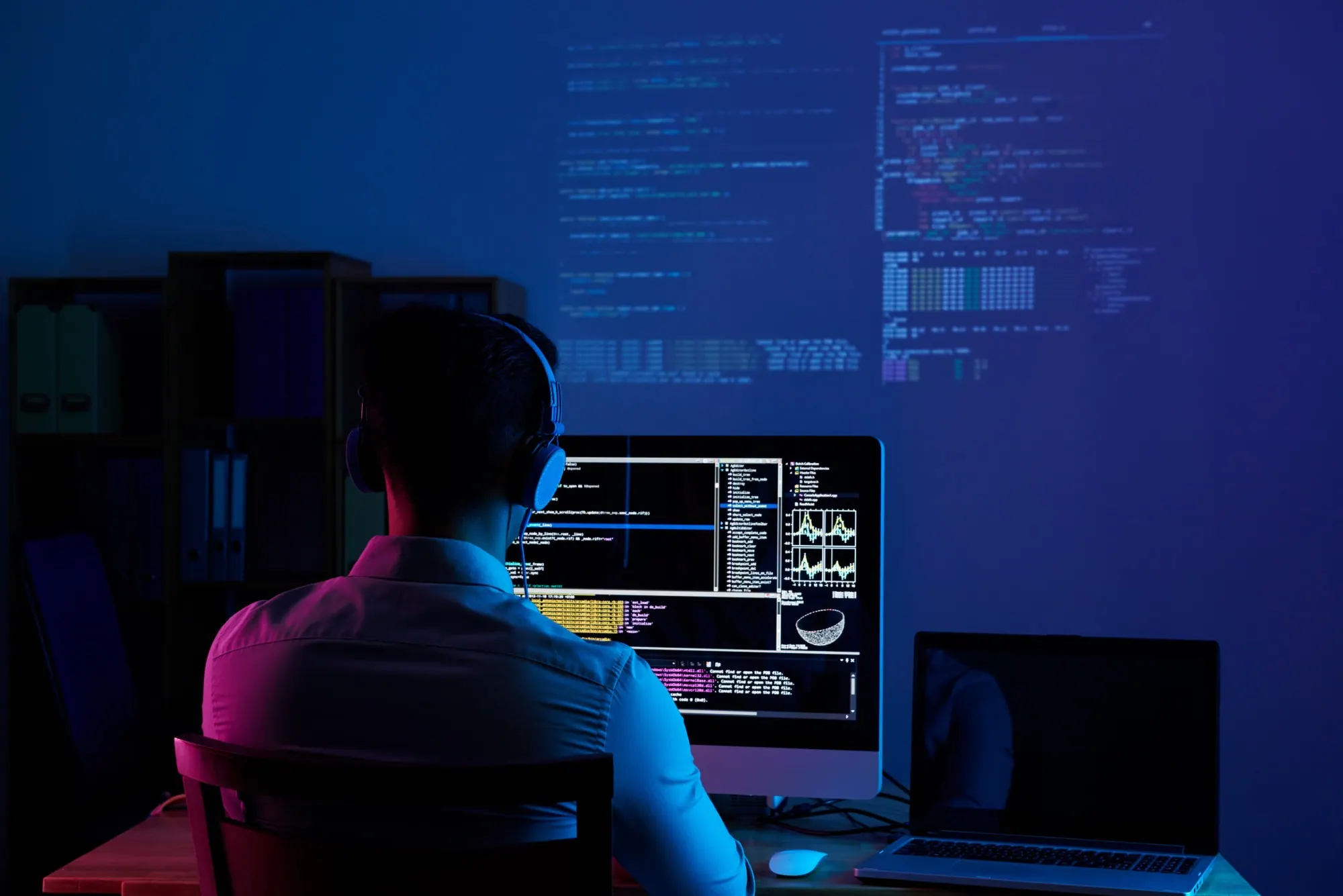 Un développeur casque sur les oreilles travaille sur son code, projeté en grand sur le mur
